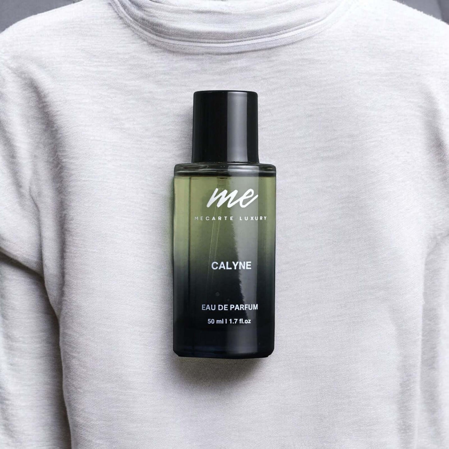 CALYNE, the best travel perfume India, displayed on a grey sweater, 50 ml Eau de Parfum bottle.