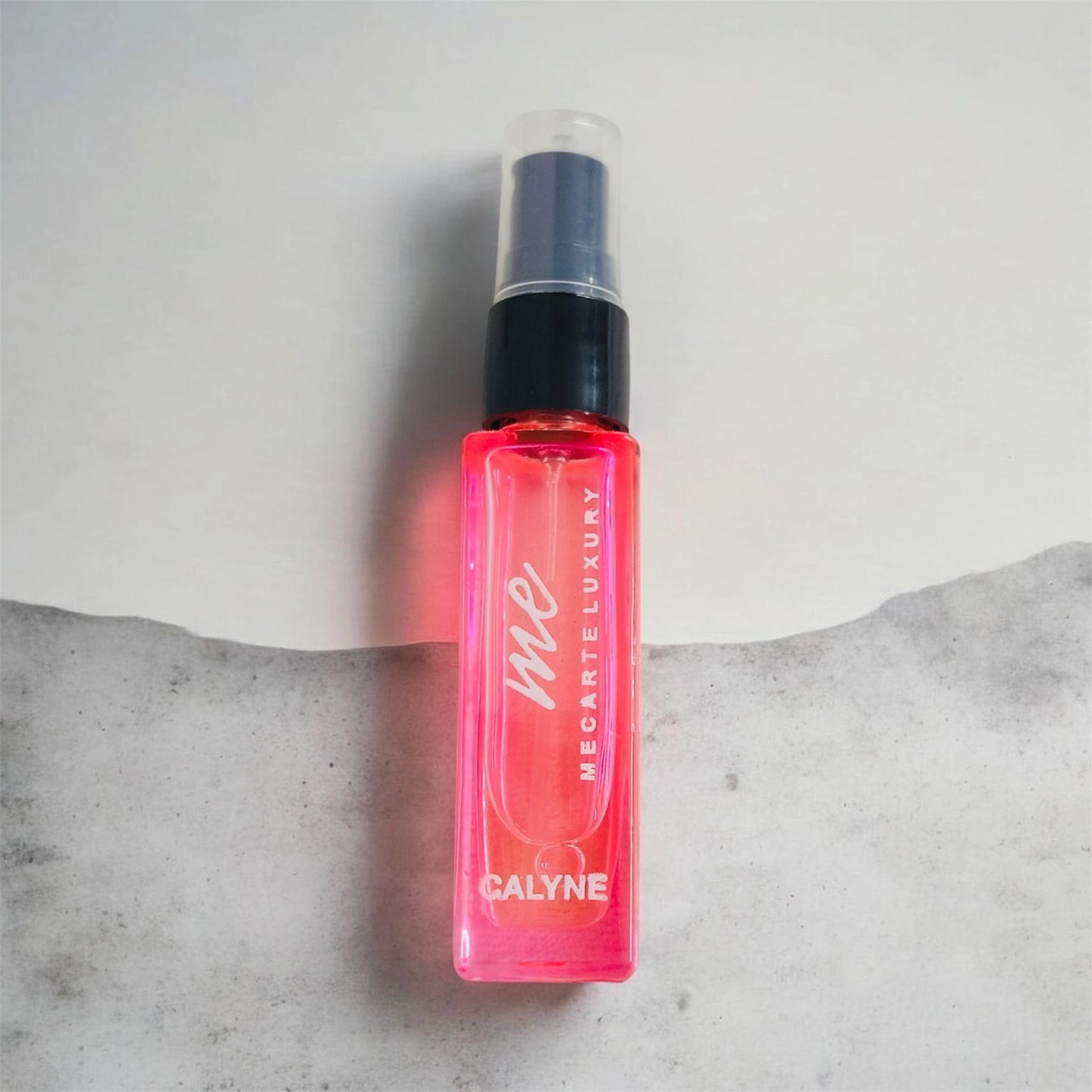 Travel size perfume Calyne Mini Perfume 8ml in a vibrant pink spray bottle on a minimalist background.