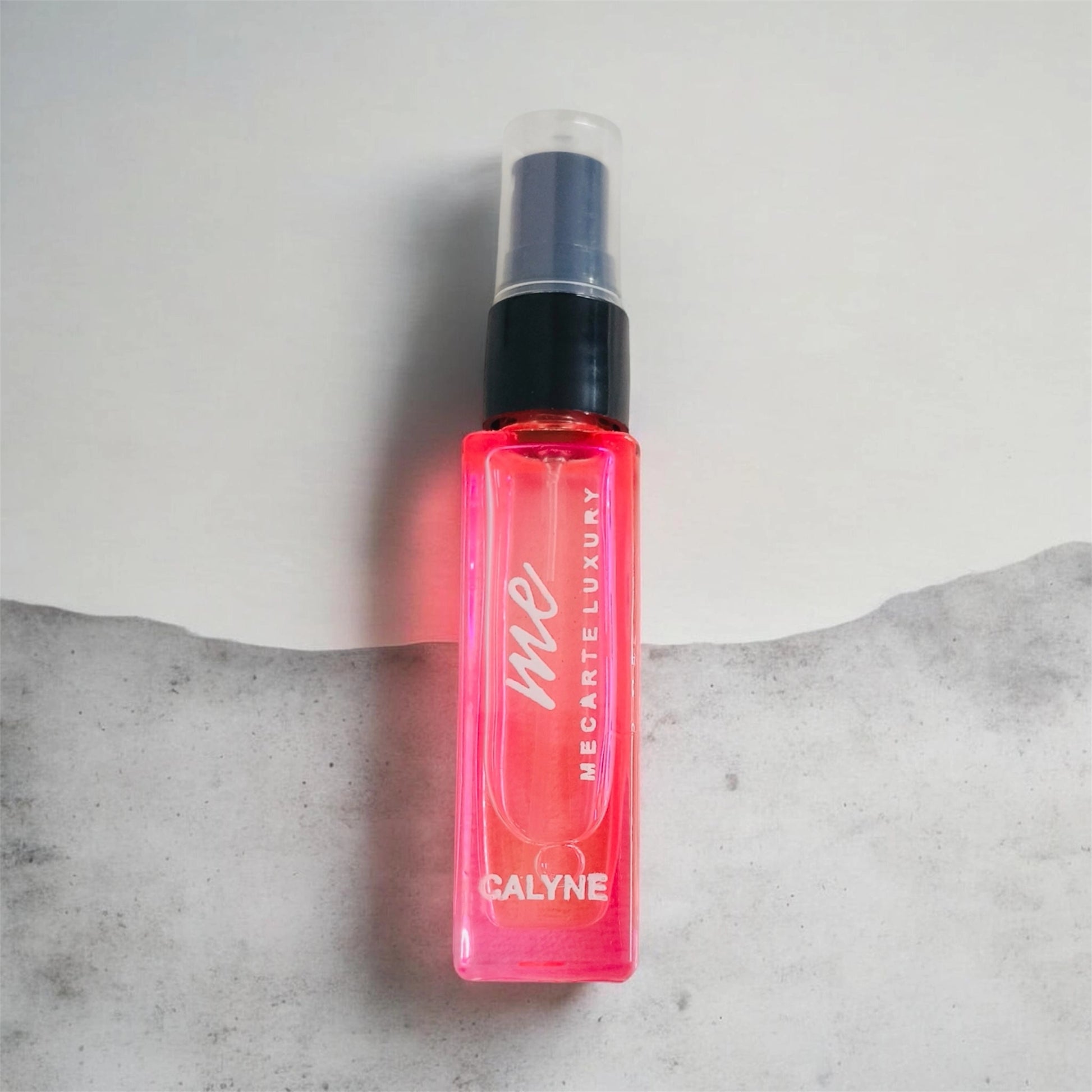 Travel size perfume Calyne Mini Perfume 8ml in a vibrant pink spray bottle on a minimalist background.