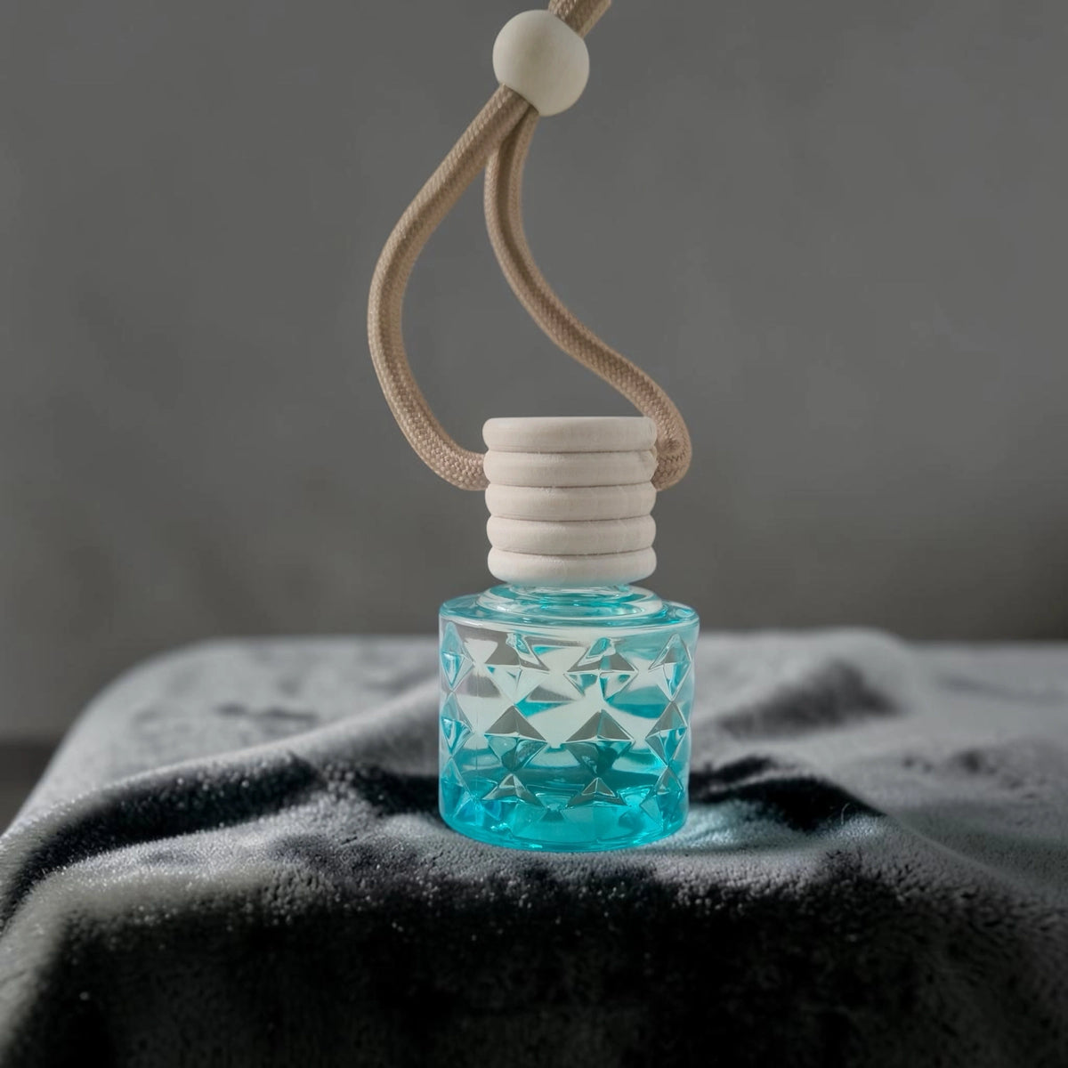 ME HHH Gold car perfume in a stylish blue glass bottle with a beige cord hanging.